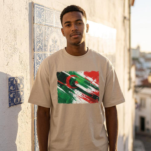 Algeria Les Fennecs Sand. Man wearing a beige t-shirt with a colorful graphic design, standing outdoors.