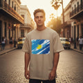 Argentina Albiceleste Sand Mode. Man wearing a beige t-shirt with a colorful graphic on a street scene