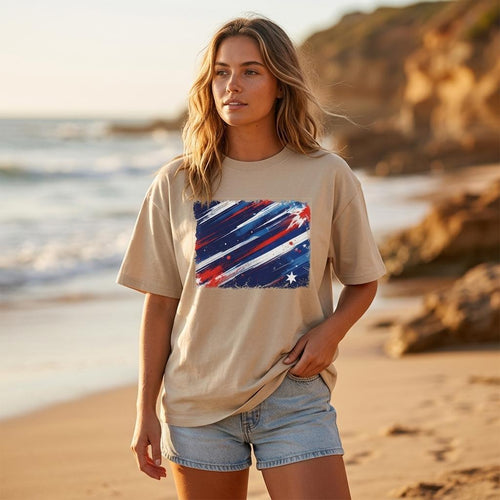 Australia Socceroos Sand. Woman wearing a beige t-shirt with a colorful graphic on a beach