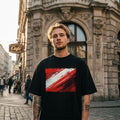 Austria Das Team Dark. Man wearing a black t-shirt with a red and white design in an urban setting