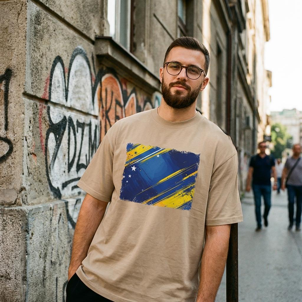 Bosnia and Herzegovina Dragons Sand. Man wearing a beige t-shirt with a colorful graphic design, standing on a street with graffiti.