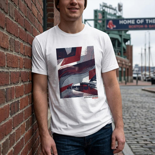 Person wearing a white t-shirt with a graphic design, standing against a brick wall with a stadium in the background.