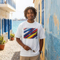 Cape Verde Tubaroes Azules Light. Man wearing a white t-shirt with a colorful graphic design, standing in a coastal alleyway.