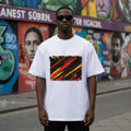 Germany Die Mannschaft Light Mode. Man wearing a white t-shirt with a colorful abstract design in front of a graffiti-covered wall.