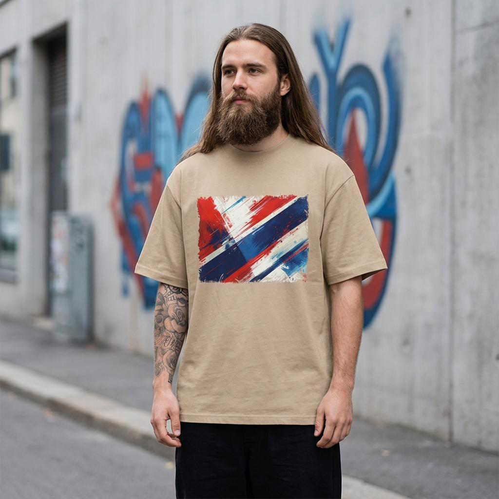 Norway Vikings Sand. Man wearing a beige t-shirt with a colorful graphic design in front of a graffiti-covered wall.