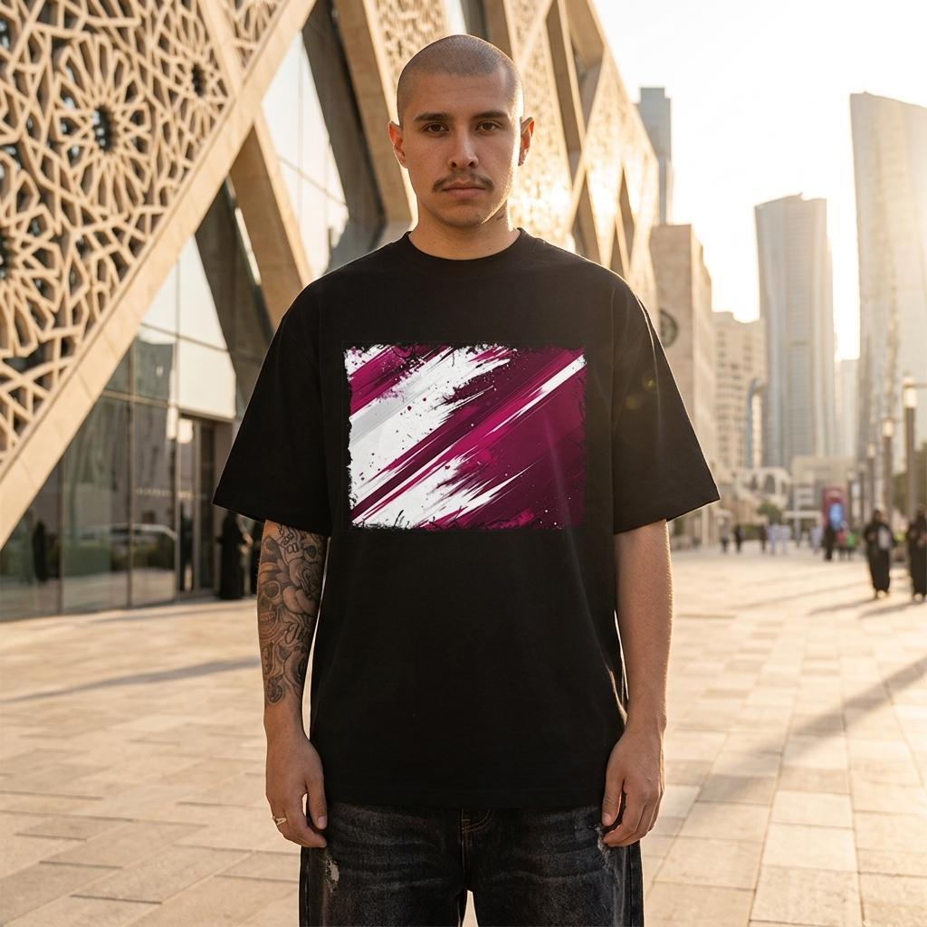 Qatar Al-Annabi Dark. Man wearing a black t-shirt with a colorful abstract design in an urban setting