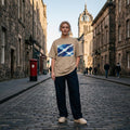 Scotland Tartan Army Sand. Person wearing a beige t-shirt with a graphic design on a cobblestone street.