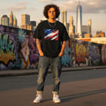 USA Glory Dark Mode. Person wearing a black t-shirt with an American flag design, standing in front of a graffiti-covered wall with city skyline in the background.