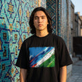 Uzbekistan White Wolves Dark. Person wearing a black t-shirt with a colorful design in front of a mosaic wall.